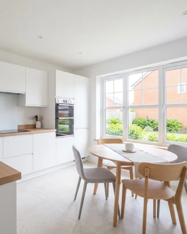 White kitchen with a wooden worktop and a round dining table by the window
