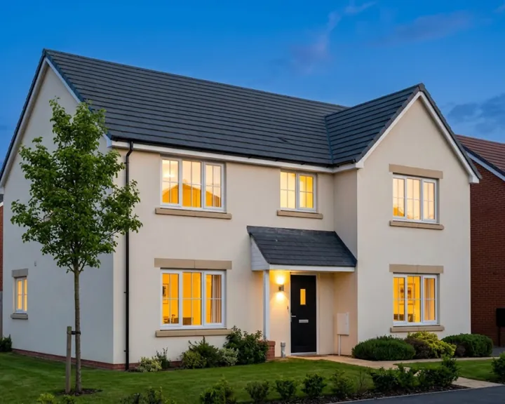 Cream rendered detached house at dusk with its windows lit